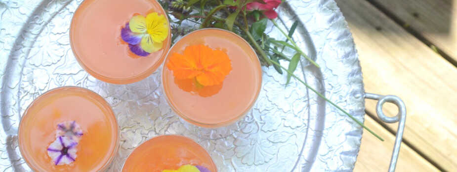 tray with 4 glasses of an orange drink with edible flowers