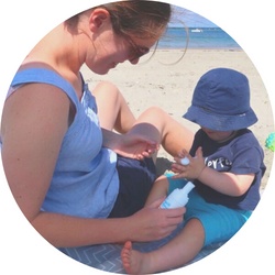 Woman sitting with child on the beach and washing hands