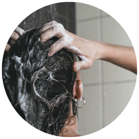 woman in shower washing her hair with shampoo