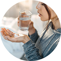 fille avec un verre d'eau et des pilules à la main