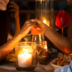 Man en vrouw houden handen vast bij diner bij kaarslicht